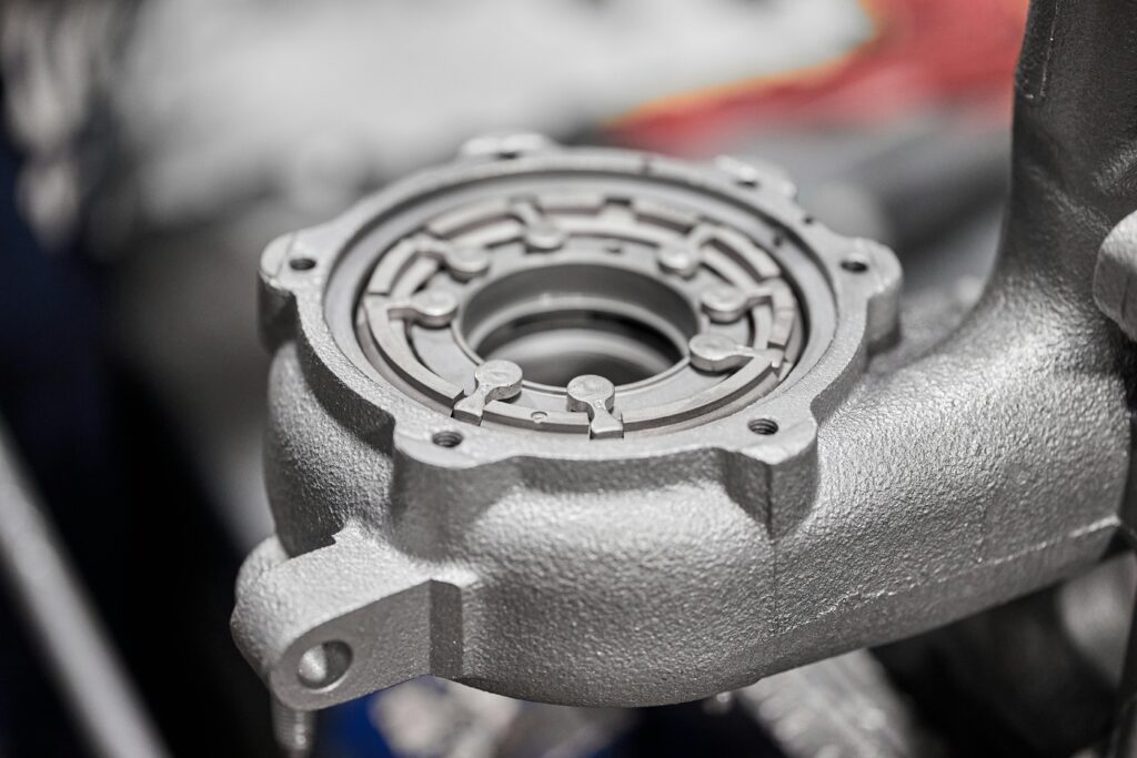 Detailed image of a metallic car component in a workshop setting, highlighting intricate metalwork.